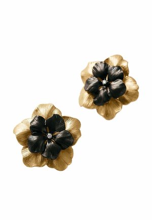 Pendientes en forma de flor dorados y negros con pétalos texturizados y una pequeña gema central sobre fondo blanco.