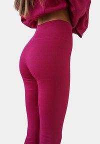 Aansluitende geribde leggings in een diepe magenta kleur; voorzien van een hoge elastische tailleband en een soepele textuur door het geheel.