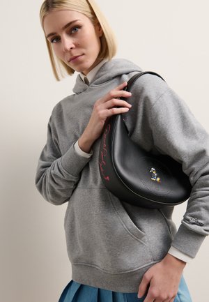Black leather bag with a rounded shape, featuring perforations and a cartoon character detail. It is accented with red text.