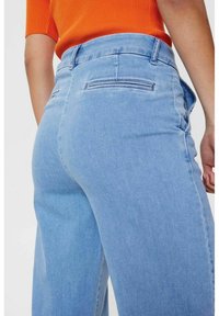 Gaisni zili džinsi ar augstu vidukli, ar aizmugures kabatām, taisnas kāju dizainu un gludu tekstūru.