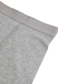 Szare bawełniane legginsy z miękkim elastycznym paskiem w talii, charakteryzujące się gładką teksturą i subtelnymi detalami przeszycia.