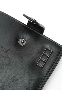 Black leather wallet featuring a textured surface, round silver snap button, and geometric metal accent with three rectangles.