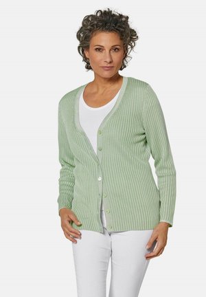 Lichtgroene geribde cardigan gemaakt van zachte stof, met een V-hals, knopen aan de voorkant en lange mouwen. Gekozen boven een witte top.
