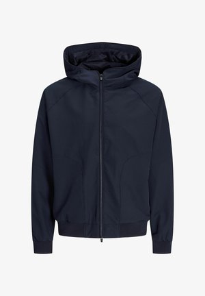 Tumes sinise värvi jope, millel on täislukuga, kapuuts, soonikkoes mansetid ja sile materjal minimaalsete õmblustega. Kerge ja lihtne disain.