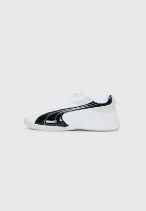 White athletic shoe with black curved stripe on side, low profile sole, and lace-up closure, shown from the right side on a white background.