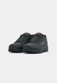 Pair of black and red Nike sneakers with visible laces and textured soles, angled slightly to the left on a plain white background.
