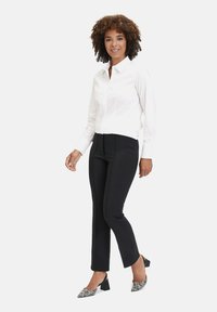 Weißes Hemd mit Knöpfen, schwarze, eng anliegende Hose und schwarz-weiße gemusterte High Heels. Glatter Stoff, strukturiertes Design und maßgeschneiderte Passform.
