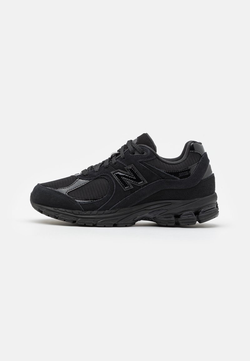 Baskets noires New Balance 2002R avec superpositions en mesh et daim, fermeture à lacets, semelle amortissante et logo de la marque sur le côté.