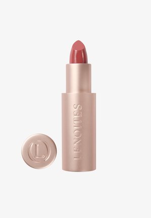 Lápiz labial en un tubo cilíndrico color oro rosa mate, con punta redondeada y base circular con logo en relieve. Color: rosa apagado.