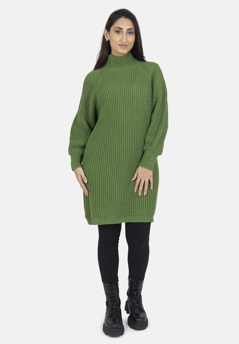 Abito maglione in verde scuro con colletto alto, texture a costine e maniche lunghe, abbinato a leggings neri e stivali alla caviglia.
