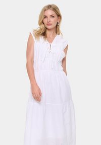 Rochie albă fără mâneci, cu un arc la gât, cu detalii brodate, talie strânsă și un design cu fuste suprapuse.