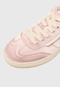 Baskets en satin rose clair avec bout rond, semelle en caoutchouc et lacets beiges. Présente des accents cousus et un patch logo sur le côté.