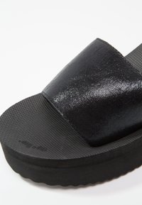 Černá nazouvací sandálová obuv s lesklým strukturálním páskem a vroubkovanou gumovou podrážkou pro lepší přilnavost. Design zahrnuje tvarovanou stélku.