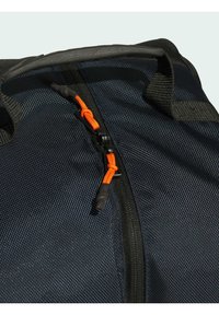 Svart texturerad tygresväska med en orange dragsko och svart dragkedja, med ett vadderat handtag för bättre grepp.