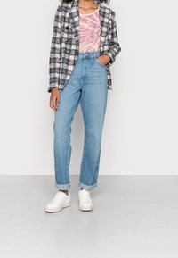 Wollen mix blazer met een ruitpatroon in marineblauw en roomwit, lichtroze tie-dye shirt, hoge taille, lichtblauwe denim jeans, en witte sneakers.