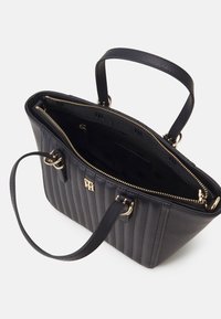 Schwarze vertikal gepolsterte Lederhandtasche mit goldenen Beschlägen, einem Reißverschluss und doppelten oberen Griffen. Das Innere ist mit einem markenspezifischen Muster ausgestattet.