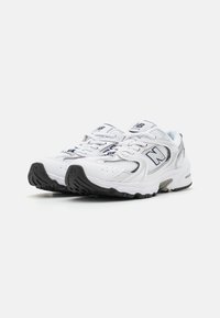 Baskets de course blanches avec des empiècements en maille et en synthétique. Comprend des lacets, un col rembourré et une semelle en caoutchouc noir avec une semelle texturée.