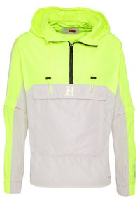 Neon żółta i jasnoszara kurtka przeciwwiatrowa, z kapturem, przednią kieszenią, zamkiem błyskawicznym na pół długości i akcentami na sznurku. Lekka, teksturowana tkanina.