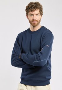 Sweatshirt bleu marine en mélange de coton, avec un col ras du cou côtelé, des boutons décoratifs à l'épaule et des surpiqûres contrastées sur les manches.