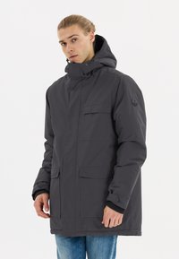 Mörkgrå vattentät parka med hög krage, justerbar huva, framfickor och elastiska ärmar. Har en logotyp på vänster ärm.