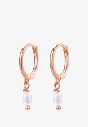 Pendientes de aro en oro rosa con pequeñas perlas blancas colgantes. Los pendientes tienen un acabado liso y una forma redonda. Vista en primer plano cerca de la oreja.