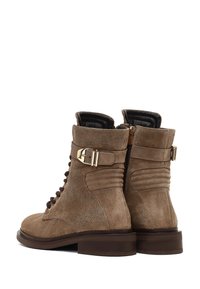 Bottines en daim marron avec un devant lacé, fermeture éclair et un détail de boucle dorée. Panneaux texturés et talons empilés.