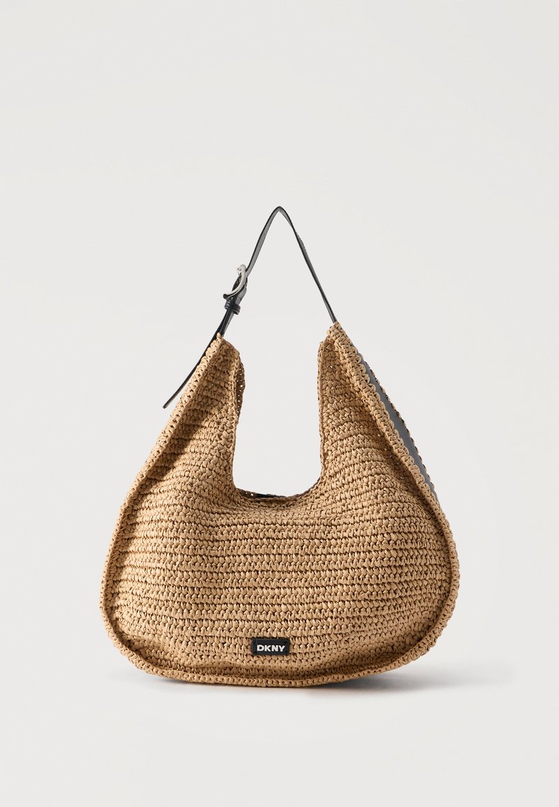 Καφέ υφαντή τσάντα ώμου με μαύρο ρυθμιζόμενο ιμάντα και μικρό μαύρο λογότυπο DKNY στο μπροστινό μέρος, τοποθετημένη σε απλό φωτεινό φόντο.