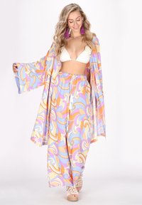 Lehký, vzorovaný kimono s vířícími pastelovými barvami. V kombinaci s volnými kalhotami a bílým bikinovým topem. Sandály na klínu jsou součástí.