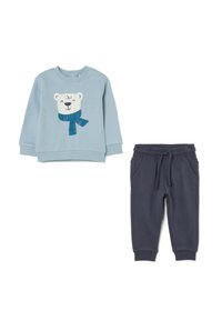 Hellblaues Sweatshirt mit einem grafischen Druck eines Eisbären und einem blauen Schal, kombiniert mit dunkelblauen, weichen Jogginghosen mit einem elastischen Bund.