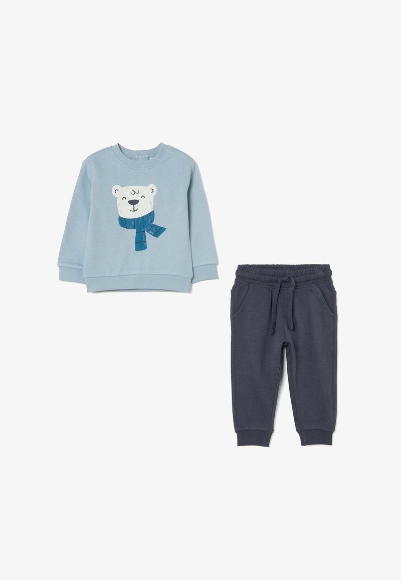 Hellblaues Sweatshirt mit einem grafischen Druck eines Eisbären und einem blauen Schal, kombiniert mit dunkelblauen, weichen Jogginghosen mit einem elastischen Bund.