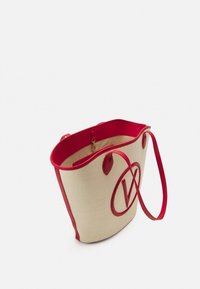 Tygväska i vävt beige material med röda detaljer. Har en stor röd 'V' logotyp, två handtag och en dragkedja upptill.