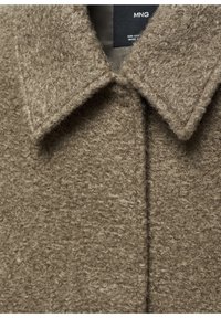 Brown textured wool coat featuring a pointed collar and visible seams. The fabric has a soft, fuzzy appearance and a minimalistic design.