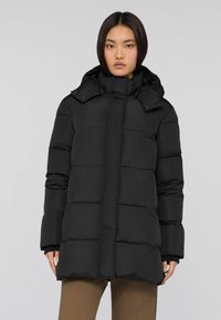 Schwarze Puffjacke mit hohem Kragen und Frontreißverschluss. Verfügt �über Karostitching und zwei Seitentaschen. Geeignet für kaltes Wetter.