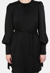 Black dress featuring a high neck, long puff sleeves, and a cinched waist with a tie. Smooth texture with minimal detailing.