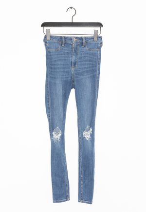 Skinny blue denim jeans with a distressed design, featuring two knee rips, five-pocket styling, and a standard waistband.