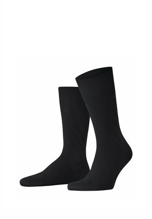 Paar schlichte schwarze Socken bis zur Hälfte der Wade mit gerippten Bündchen vor weißem Hintergrund.