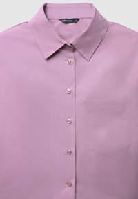 Camicetta leggera viola chiaro realizzata in tessuto liscio. Presenta un collo classico e una tasca sul petto con sei bottoni coordinati.
