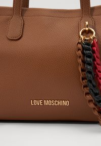 Brown textured leather handbag with a gold logo reading "LOVE MOSCHINO" and a multicolored braided chain accent in red, black, and brown.