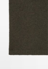 Maglione a maglia verde scuro con orlo a coste e cuciture verticali, realizzato in un tessuto morbido e strutturato, dal design semplice e senza fronzoli.