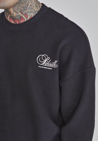 Felpa navy con un grande logo in bianco sulla parte sinistra del petto, colletto a costine e vestibilità comoda. Tessuto in cotone con una superficie liscia.