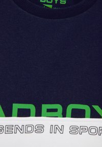 Tricou din bumbac bleu marin cu text mare verde care spune "BĂIEȚI" și o bandă albă la baza acestuia pe care este scris "LEGENDĂ ÎN SPORT."