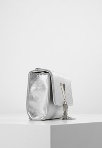 Borsa in pelle argentata con finitura testurizzata, forma rettangolare e chiusura a patta. Include un accento in catena metallica e accessori a contrasto.