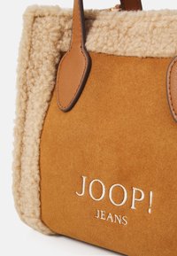 Borsa in suede marrone con manici in pelle beige e rifiniture in shearling beige, caratterizzata dal logo ricamato bianco "JOOP! JEANS".