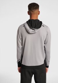 Sudadera gris con capucha negra, con textura suave, diseño ajustado y acentos negros en las mangas y el fondo.
