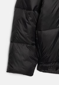 Sort puffjakke med en glat, skinnende overflade. Har kviltede sektioner, en stor krave og en sidelomme. Let og polstret design.