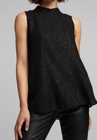 Sort ærmeløs top med høj hals, med diskret metallisk prikmønster og blødt stof. Flydende design med en flatterende silhuet.