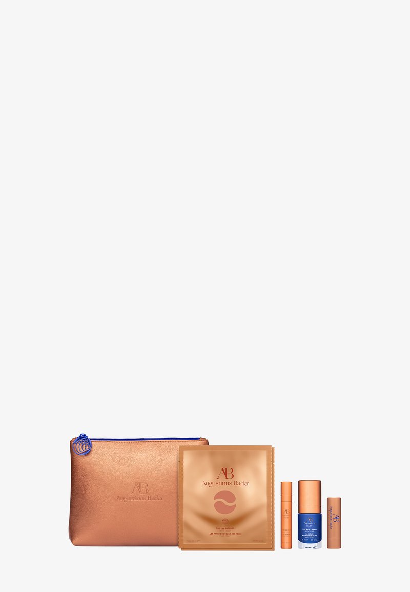 Rose gold zipper pouch with blue accents, containing a gold treatment mask, two cream bottles, and a lip product, all with branded packaging.