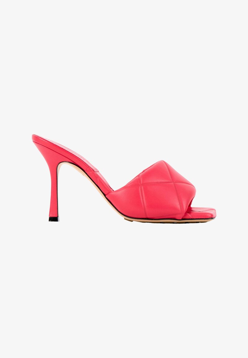 Mule à talon haut rouge avec bride large matelassée et rembourrée, talon fin sur fond blanc.