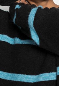 Maglione nero lavorato a maglia con righe orizzontali turchesi, caratterizzato da una finitura morbida e texturizzata e dettagli a costine ai polsini.