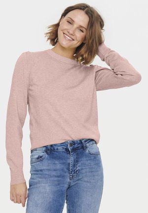 MaglIONE rosa chiaro a maglia con maniche lunghe e scollo rotondo, indossato con jeans in denim blu, caratterizzato da polsini a coste e vestibilità rilassata.